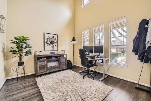 home office featuring a high ceiling, plenty of natural light, and dark hardwood / wood-style floors