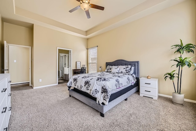 bedroom featuring ensuite bath, a raised ceiling, ceiling fan, and carpet