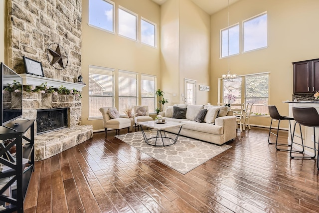 living room featuring a towering ceiling, a fireplace, dark hardwood / wood-style flooring, and a notable chandelier