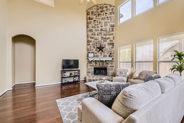 living room with a fireplace, plenty of natural light, dark hardwood / wood-style flooring, and a towering ceiling