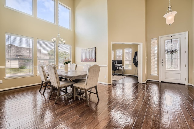 dining space featuring a high ceiling, plenty of natural light, dark wood-type flooring, and a chandelier