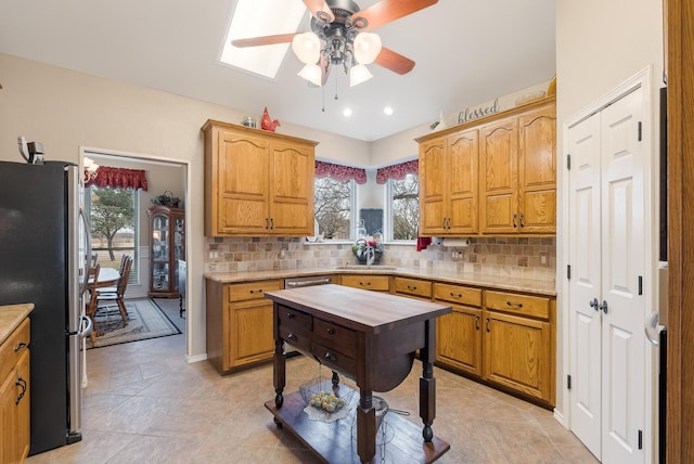 kitchen with plenty of natural light, decorative backsplash, and stainless steel fridge