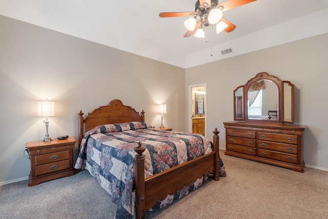 bedroom featuring ceiling fan, vaulted ceiling, light colored carpet, and ensuite bath