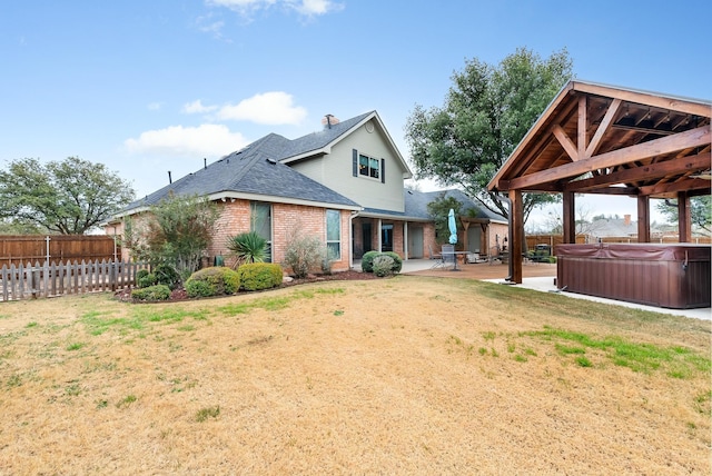 rear view of property with a patio, a gazebo, a yard, and a hot tub