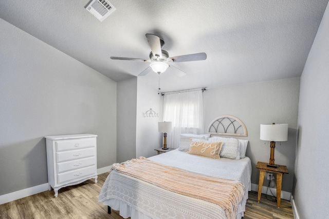 bedroom with ceiling fan, light hardwood / wood-style floors, and a textured ceiling