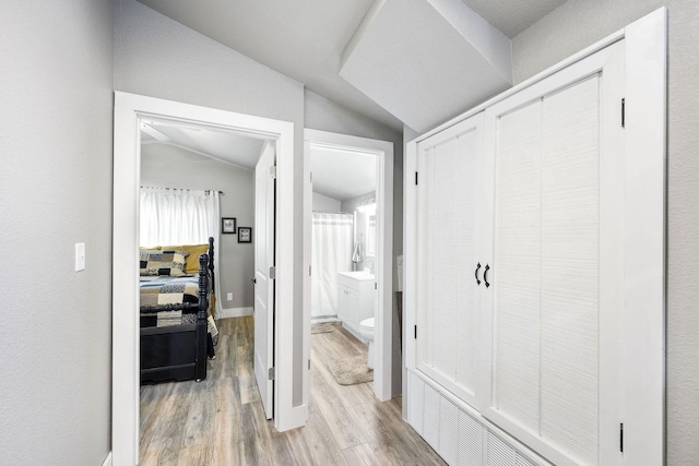 hallway featuring lofted ceiling and light wood-type flooring