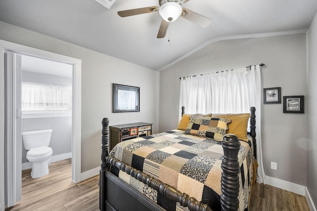 bedroom featuring ceiling fan, ensuite bathroom, light hardwood / wood-style flooring, and lofted ceiling