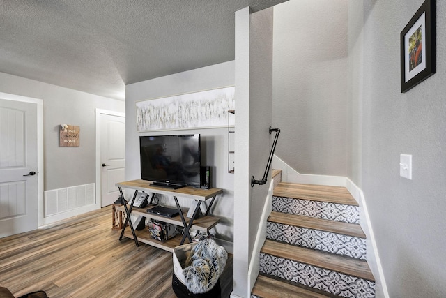 stairway featuring hardwood / wood-style floors and a textured ceiling