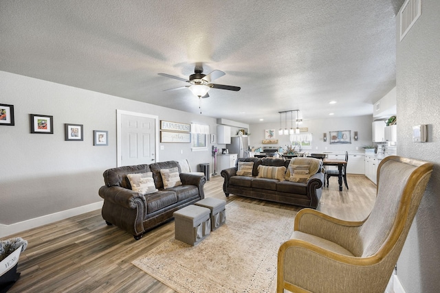 living room featuring ceiling fan, hardwood / wood-style floors, and a textured ceiling