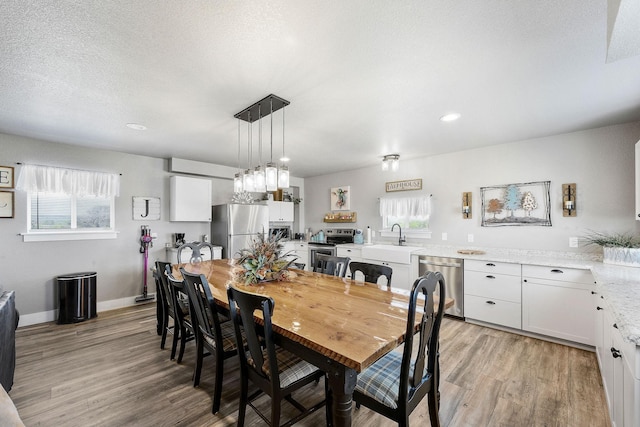 dining room with sink, light hardwood / wood-style floors, and a textured ceiling