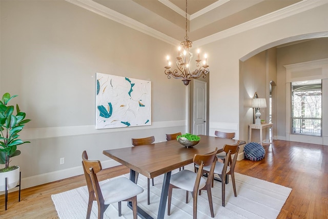 dining space with a notable chandelier, ornamental molding, and light hardwood / wood-style floors