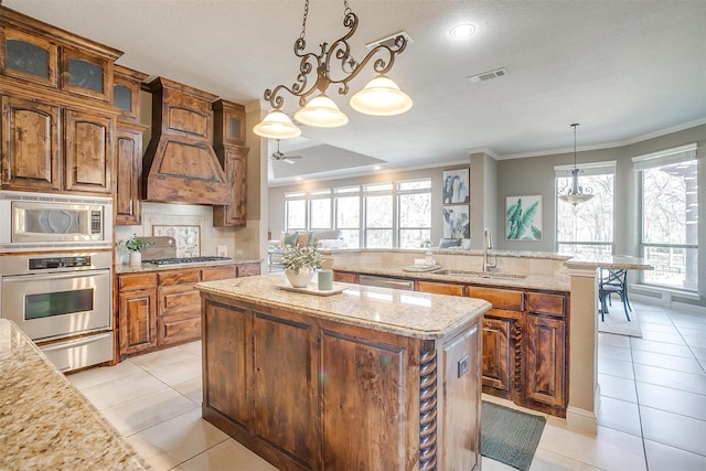 kitchen featuring light tile patterned flooring, appliances with stainless steel finishes, pendant lighting, sink, and a kitchen island with sink