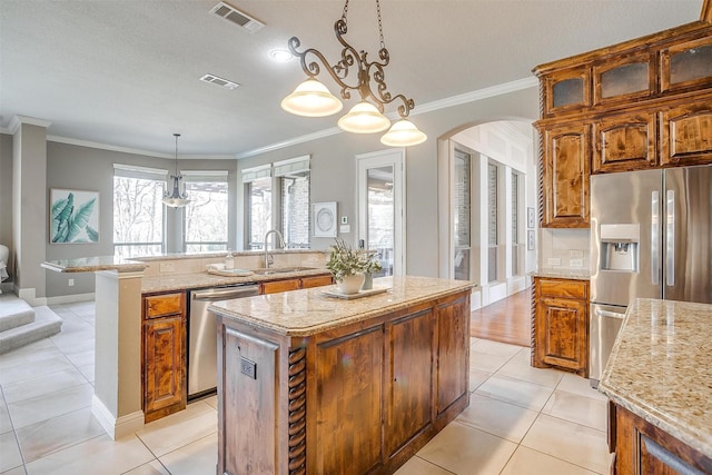 kitchen with pendant lighting, sink, light tile patterned floors, appliances with stainless steel finishes, and a kitchen island