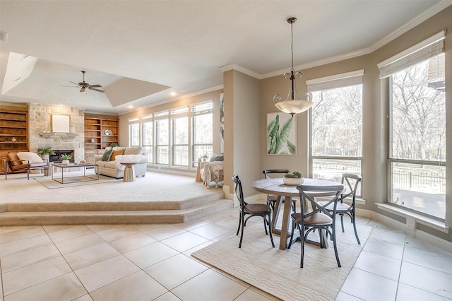 tiled dining room featuring crown molding, a fireplace, built in features, and ceiling fan