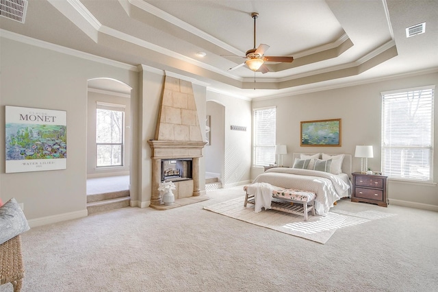 bedroom with multiple windows, a tray ceiling, crown molding, and ceiling fan