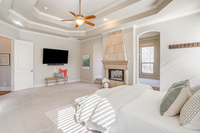 bedroom with light colored carpet, a multi sided fireplace, ornamental molding, a raised ceiling, and ceiling fan