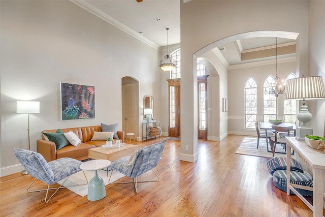 living room with ornamental molding, light hardwood / wood-style floors, a chandelier, and a high ceiling