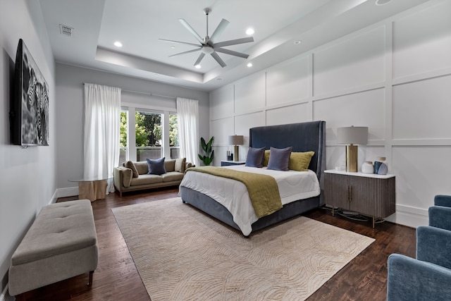 bedroom featuring ceiling fan, dark hardwood / wood-style floors, and a tray ceiling