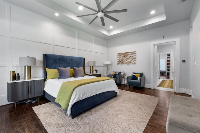 bedroom with ceiling fan, a raised ceiling, and hardwood / wood-style floors