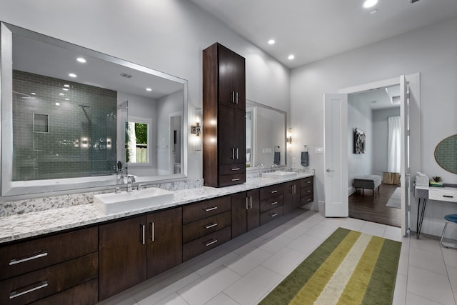 bathroom featuring tiled shower, vanity, and tile patterned flooring