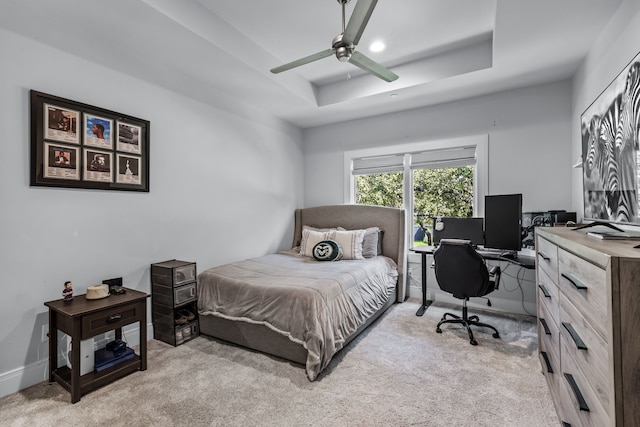 bedroom featuring ceiling fan, light carpet, and a raised ceiling