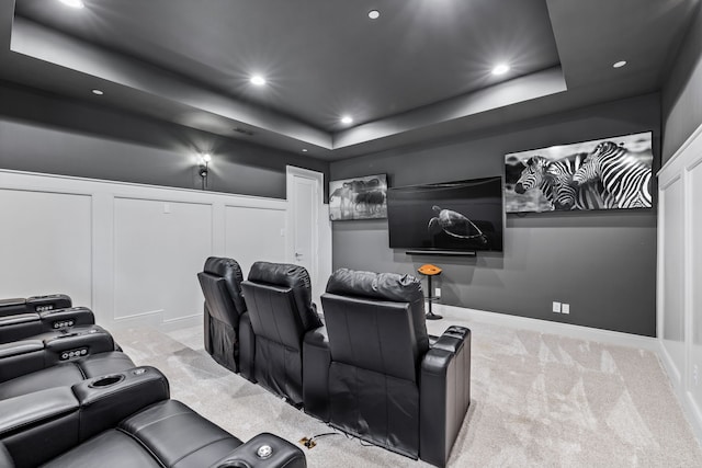 carpeted home theater with a tray ceiling