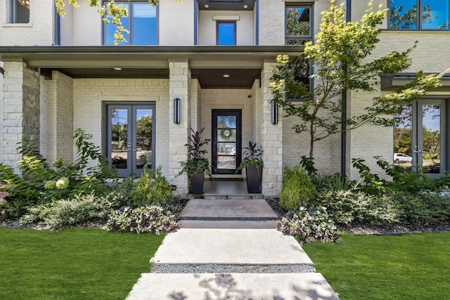 view of exterior entry featuring a lawn and french doors