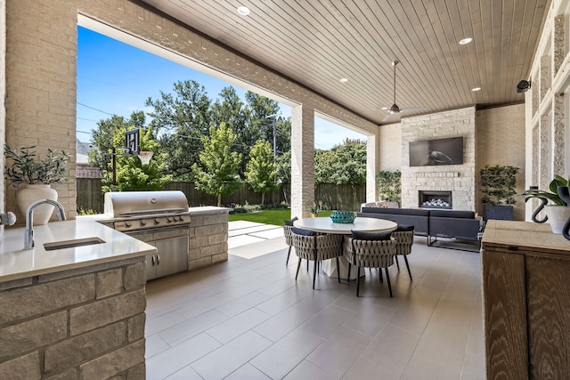 view of patio / terrace with exterior kitchen, sink, a grill, and an outdoor brick fireplace