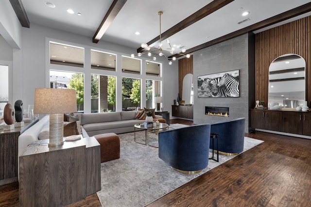 living room with dark hardwood / wood-style flooring, a tile fireplace, beam ceiling, and an inviting chandelier