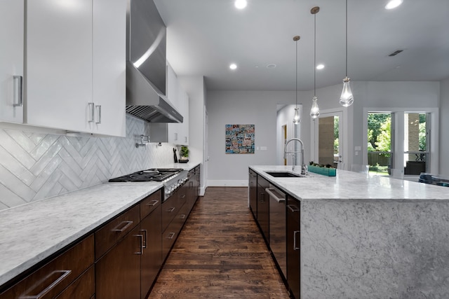 kitchen with white cabinetry, sink, backsplash, a kitchen island with sink, and stainless steel gas stovetop