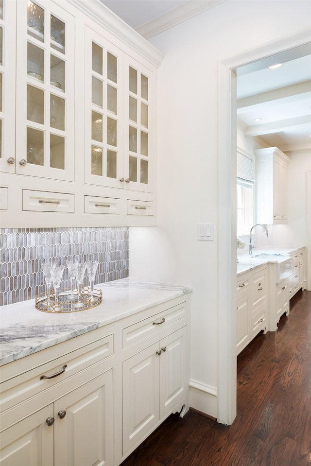 bar with light stone countertops, white cabinets, and tasteful backsplash