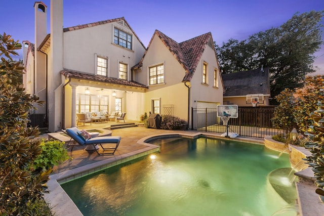 back house at dusk featuring pool water feature, a fenced in pool, and a patio