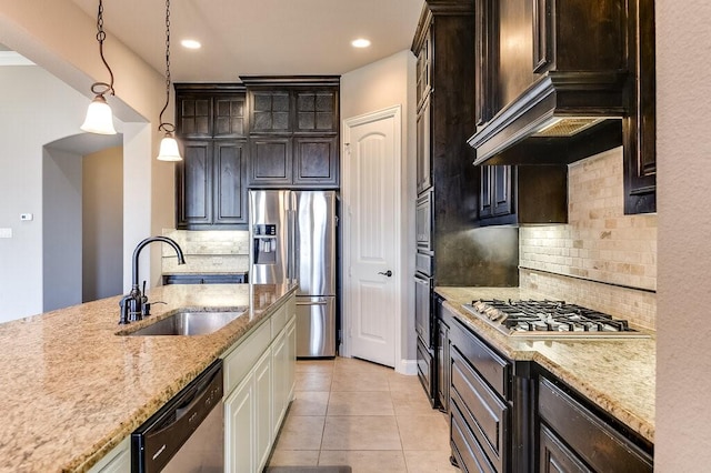 kitchen with dark brown cabinetry, appliances with stainless steel finishes, decorative light fixtures, sink, and light tile patterned floors