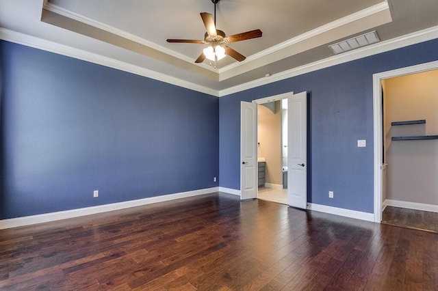 unfurnished bedroom with ensuite bathroom, a raised ceiling, ornamental molding, ceiling fan, and dark hardwood / wood-style floors