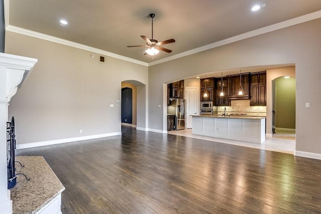 unfurnished living room featuring sink, dark wood-type flooring, ceiling fan, and ornamental molding