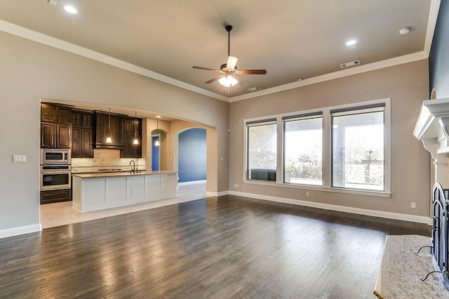 unfurnished living room featuring ceiling fan, light hardwood / wood-style floors, sink, and ornamental molding