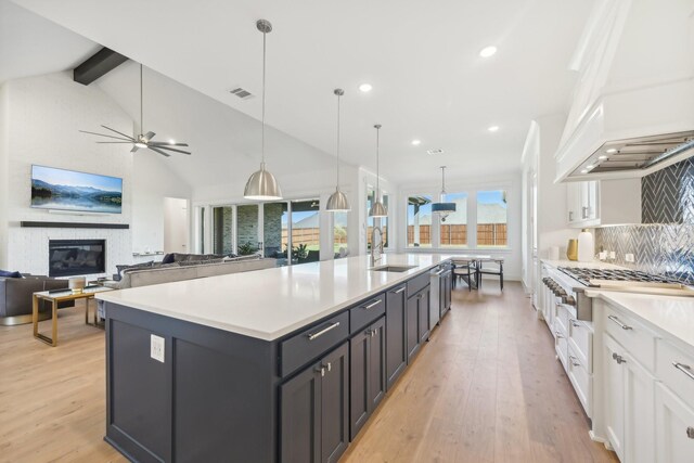 kitchen with white cabinetry, hanging light fixtures, stainless steel double oven, a large island, and a breakfast bar area