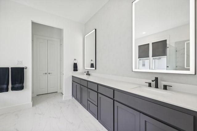 bathroom with marble finish floor, a sink, baseboards, and double vanity