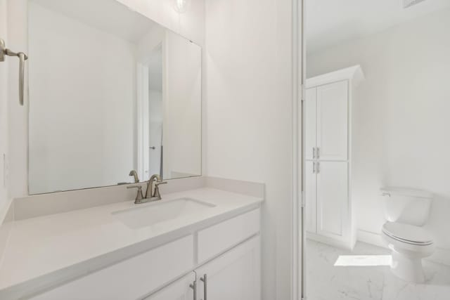 bathroom with marble finish floor, vanity, and toilet