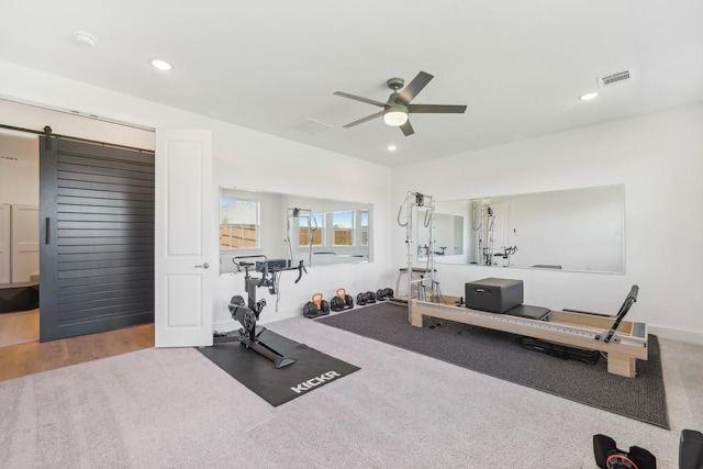 exercise room featuring ceiling fan, a barn door, visible vents, and recessed lighting