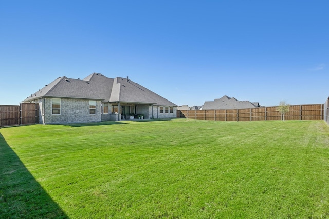 back of house featuring a fenced backyard, a lawn, and brick siding