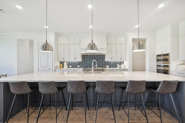 kitchen featuring white cabinets, double oven, visible vents, and a large island