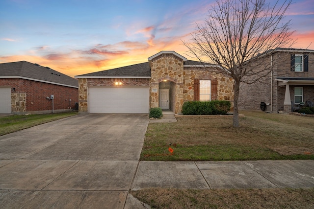 view of front of property featuring a garage, stone siding, driveway, and a lawn