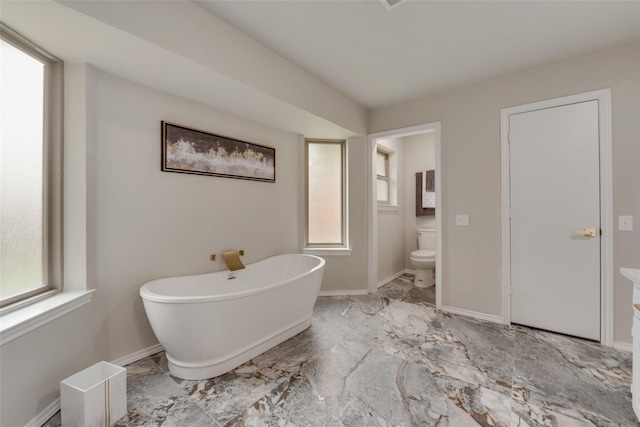 bathroom with a bath, toilet, and a wealth of natural light