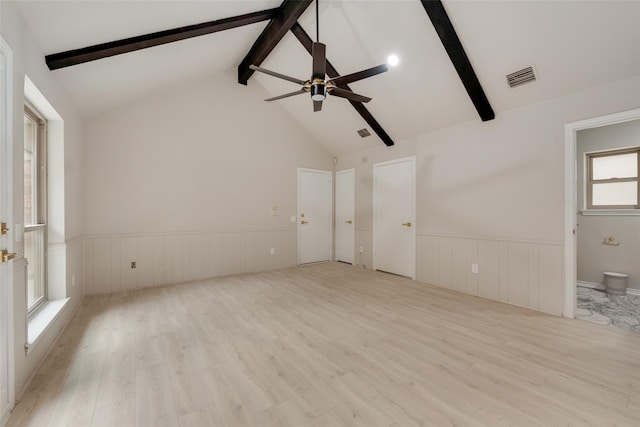 unfurnished living room featuring light wood-type flooring, beamed ceiling, and plenty of natural light