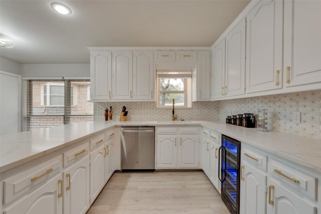 kitchen with beverage cooler, dishwasher, white cabinetry, decorative backsplash, and sink