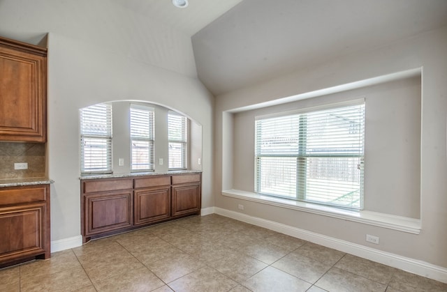 interior space featuring light tile patterned floors and vaulted ceiling