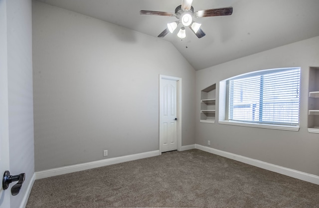 carpeted empty room featuring built in features, vaulted ceiling, and ceiling fan