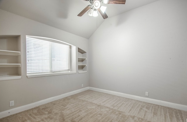 carpeted empty room with built in features, vaulted ceiling, and ceiling fan