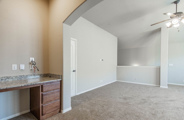 interior space featuring light carpet, vaulted ceiling, ceiling fan, and built in desk